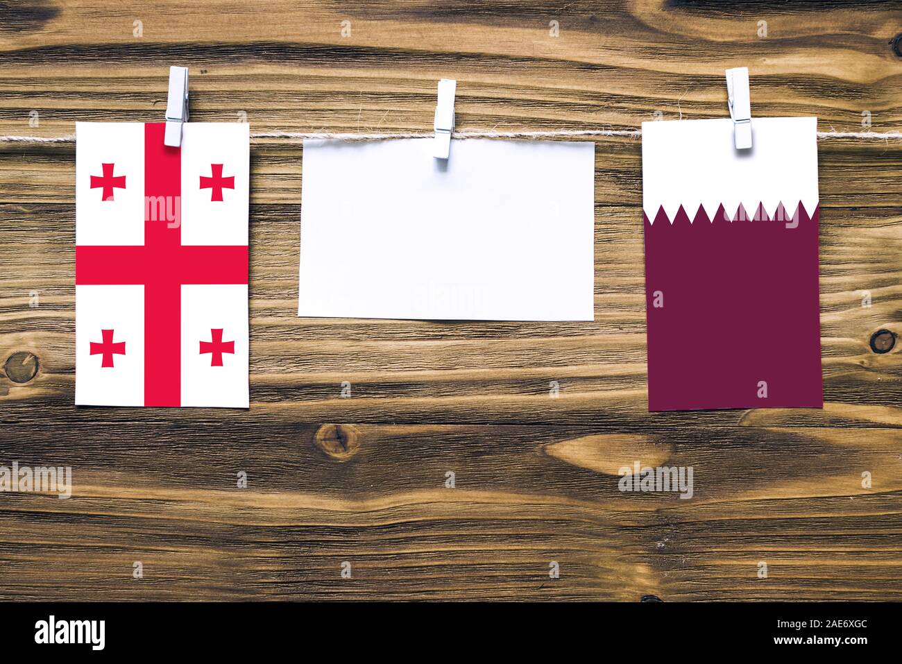 Appendere bandiere della Georgia e il Qatar attaccata alla corda con vestiti perni con copia spazio bianco sulla nota carta su sfondo di legno.Le relazioni diplomatiche essere Foto Stock