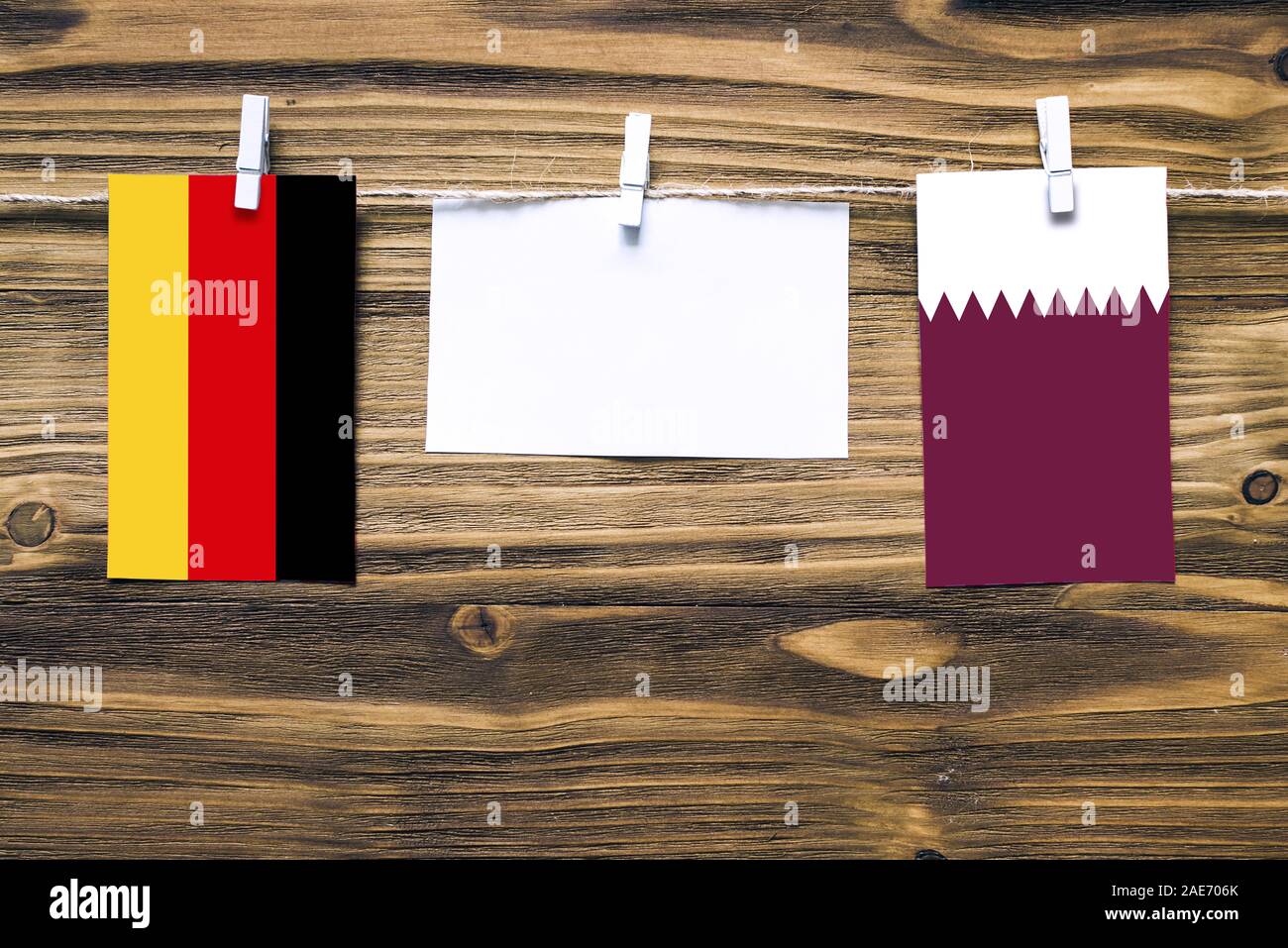 Appendere le bandiere della Germania e il Qatar attaccata alla corda con vestiti perni con copia spazio bianco sulla nota carta su sfondo di legno.Le relazioni diplomatiche essere Foto Stock