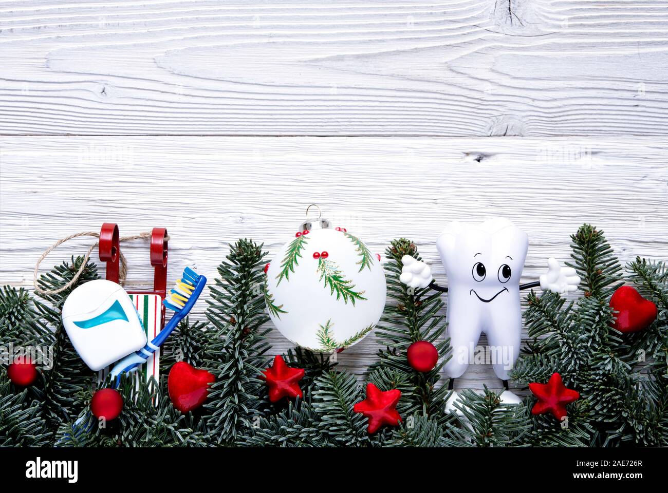 Cartoon carino dente con spazzolino e filo interdentale su sled sfondo di Natale con decorazioni in legno bianco bordo. Vista superiore, piatto laici. Foto Stock