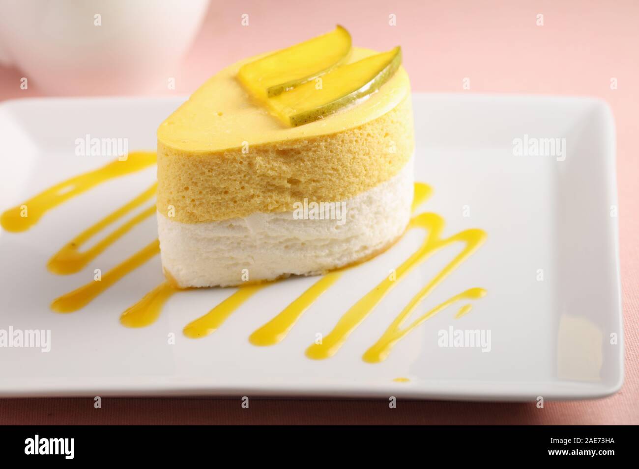 Mango e panna acida dessert guarnita con fette di mango su una lastra decorata con coulis di mango Foto Stock