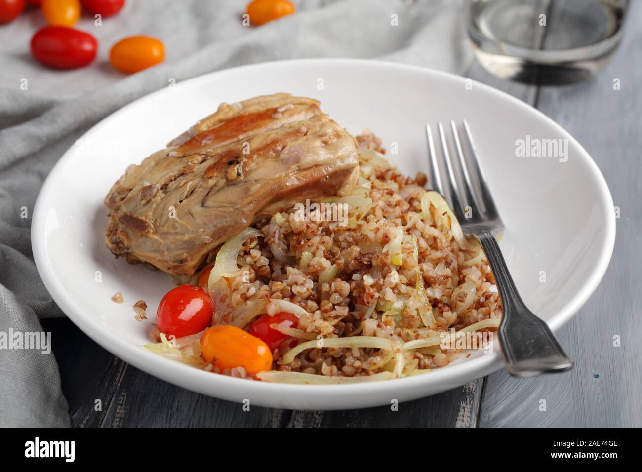 Coniglio arrosto con farinata di grano saraceno, cipolle arrosto e pomodori ciliegia Foto Stock