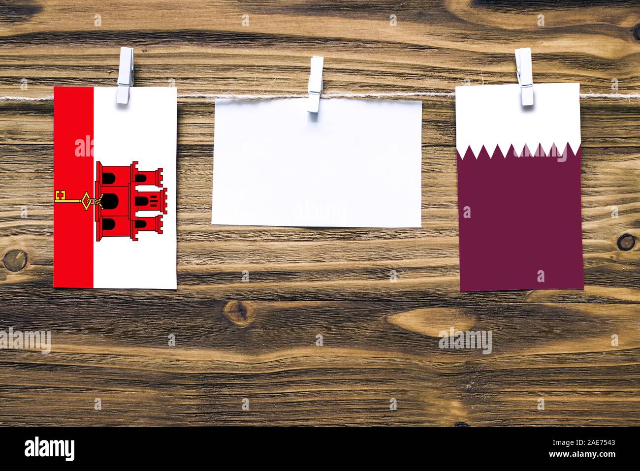 Appendere bandiere di Gibilterra e il Qatar attaccata alla corda con vestiti perni con copia spazio bianco sulla nota carta su sfondo di legno.Le relazioni diplomatiche Foto Stock