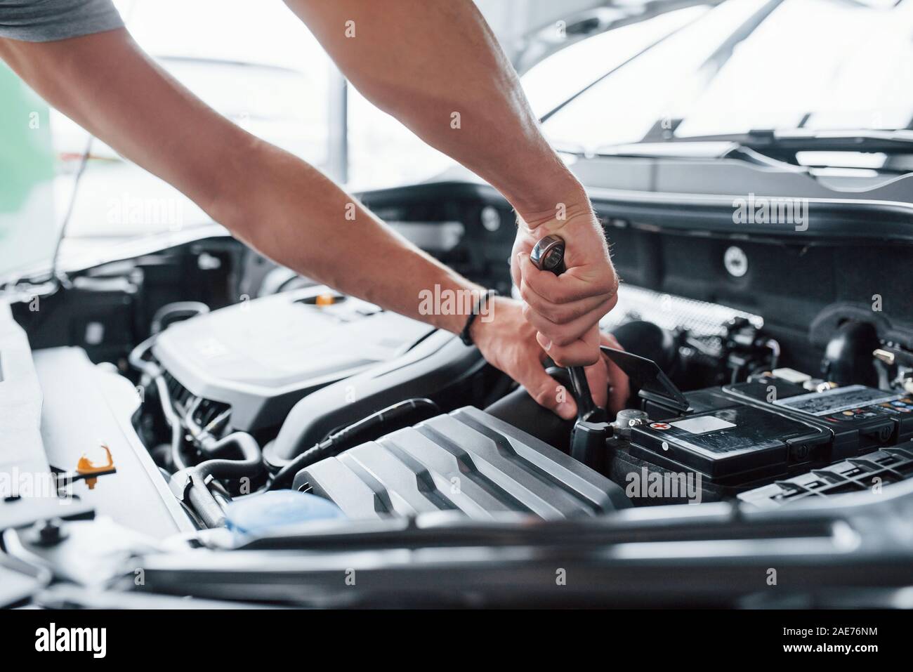 Togliere l'elemento. Processo di riparazione di auto dopo incidente. Uomo che lavora con il motore sotto il cofano Foto Stock