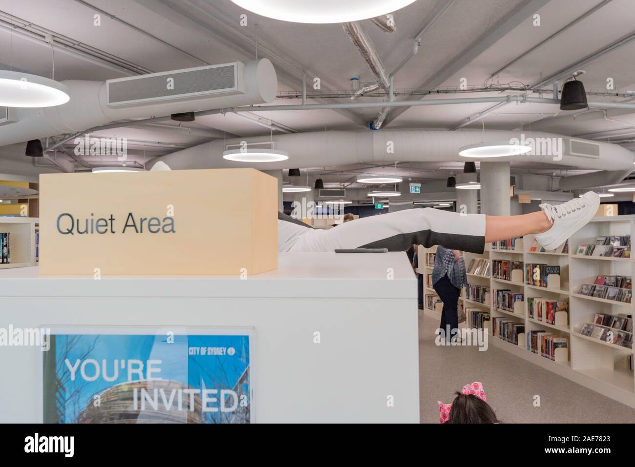 10 NOV 2019: Un contortionist punti la sua gamba tra le librerie in apertura dell'edificio di centrale e la città di Sydney Libreria nel Darling Square. Foto Stock