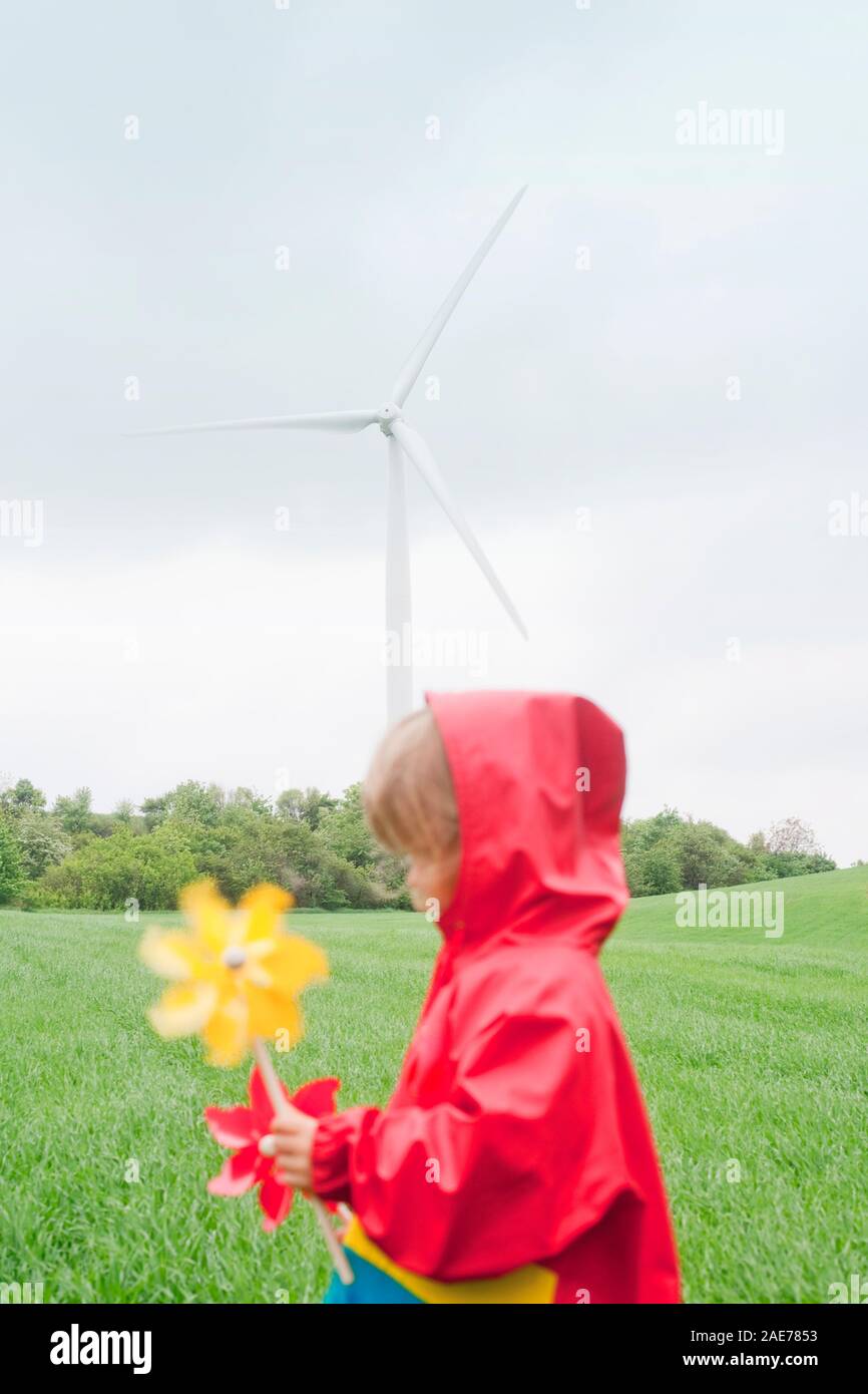 Ragazzo con due pinwheels nella parte anteriore della fattoria eolica. Foto Stock