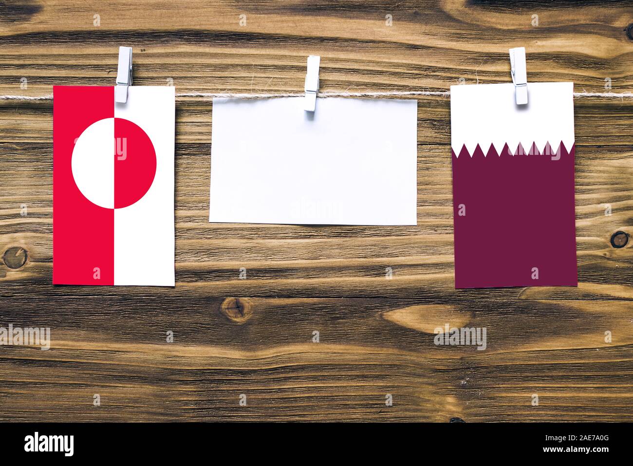 Appendere bandiere della Groenlandia e Qatar attaccata alla corda con vestiti perni con copia spazio bianco sulla nota carta su sfondo di legno.Le relazioni diplomatiche Foto Stock