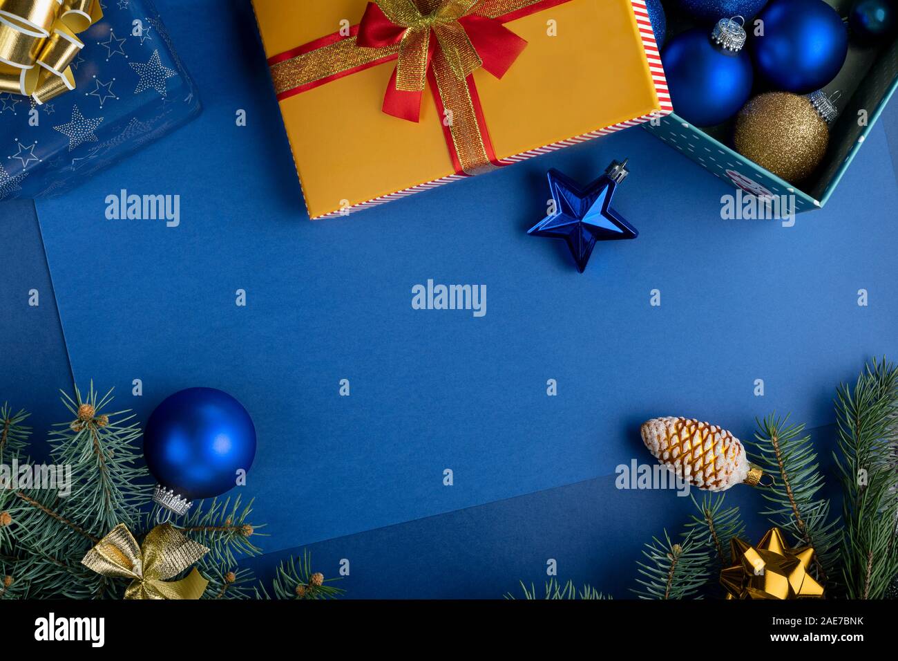 Composizione di natale con decorazioni, confezioni regalo baubles e rami di abete sul classico sfondo blu. Vacanze di Natale sfondo Foto Stock