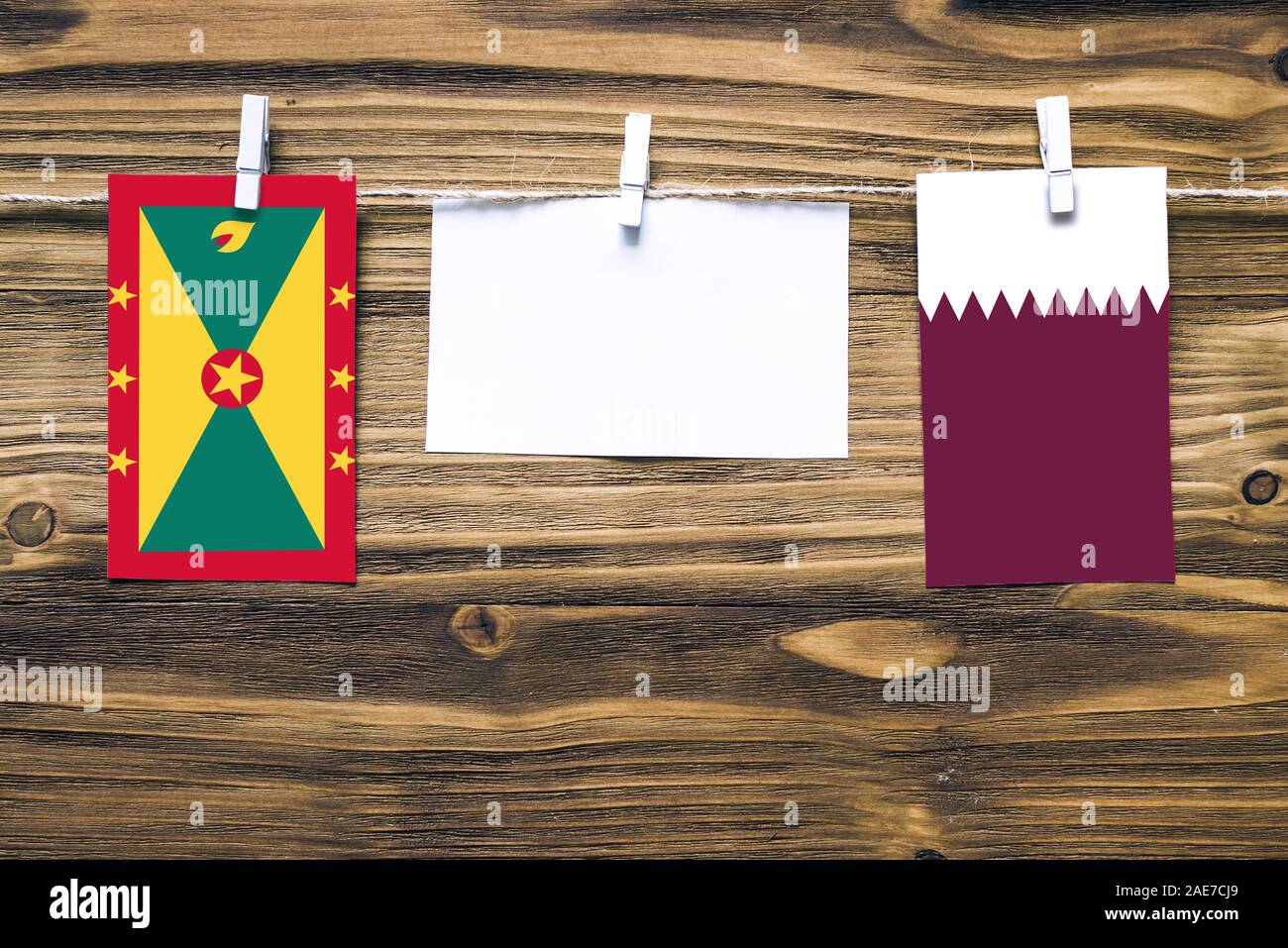 Appendere bandiere di Grenada e Qatar attaccata alla corda con vestiti perni con copia spazio bianco sulla nota carta su sfondo di legno.Le relazioni diplomatiche essere Foto Stock