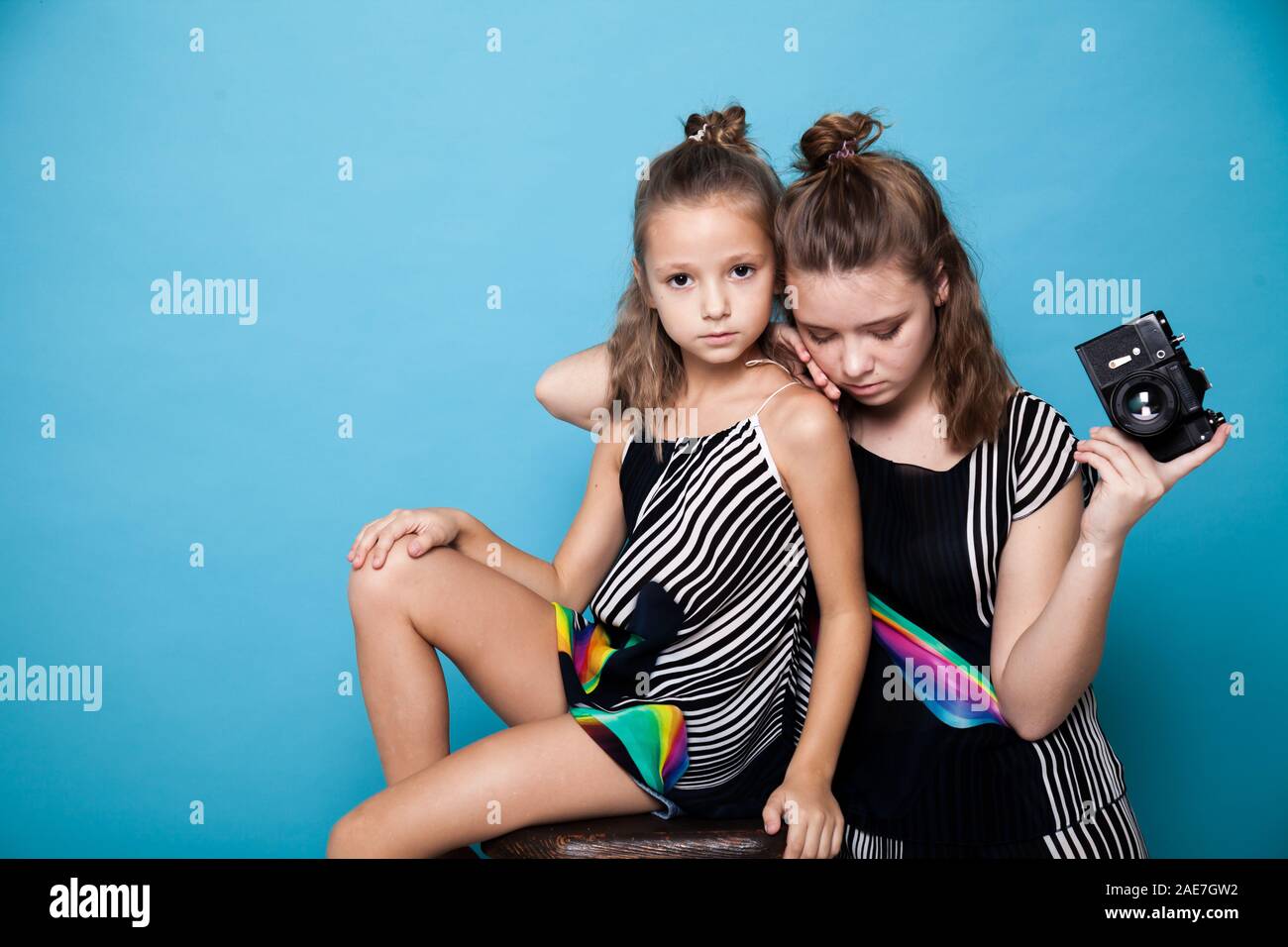 Due sorelle di moda ragazze con una telecamera su uno sfondo blu Foto Stock