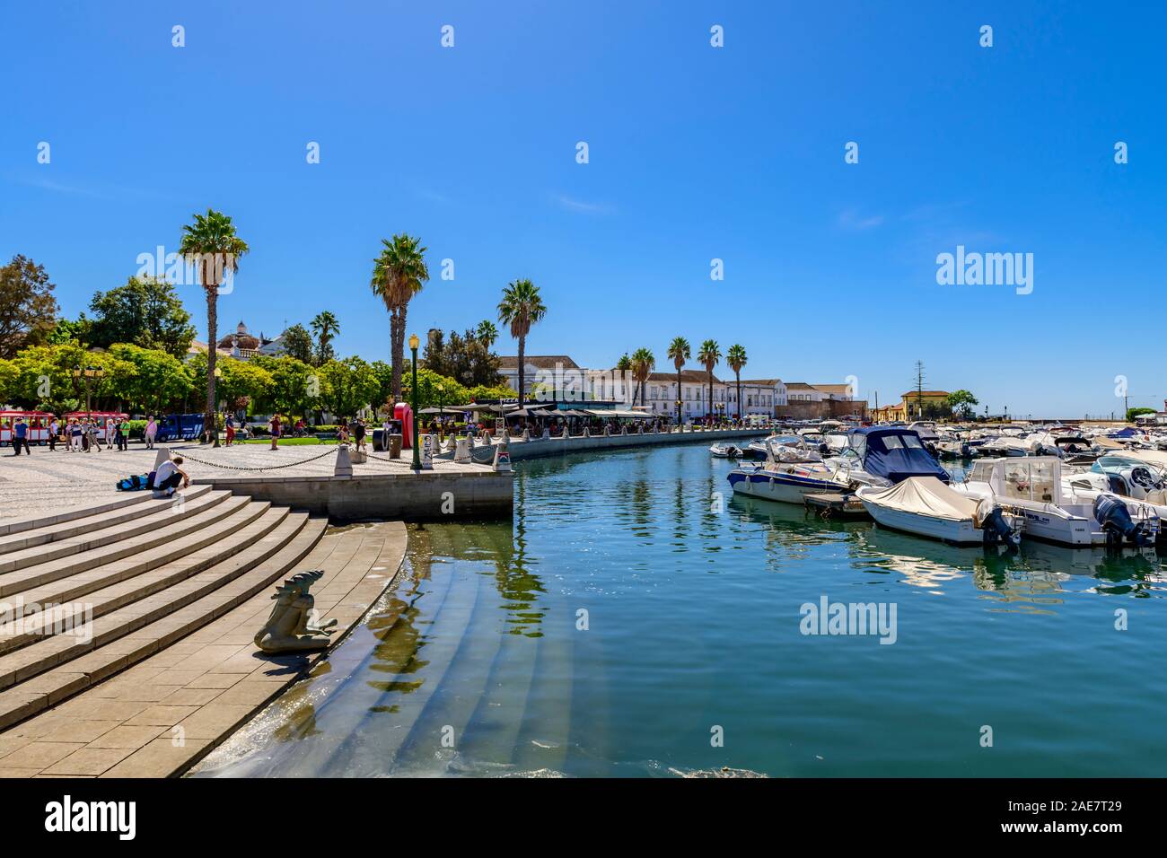Vista attraverso il porto turistico con la statua seduto sui gradini Barche e yacht ormeggiati al porto di Faro. Faro Algarve Portogallo. Foto Stock