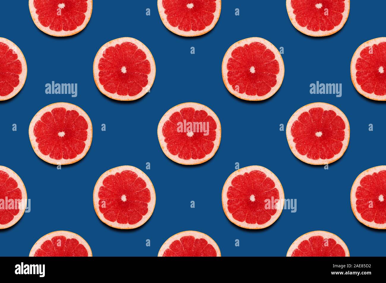 Fette di pompelmo classic seamless pattern su sfondo blu. Il minimo estate 2020 concept. Piatto, laici alla moda colore succosa. Foto Stock