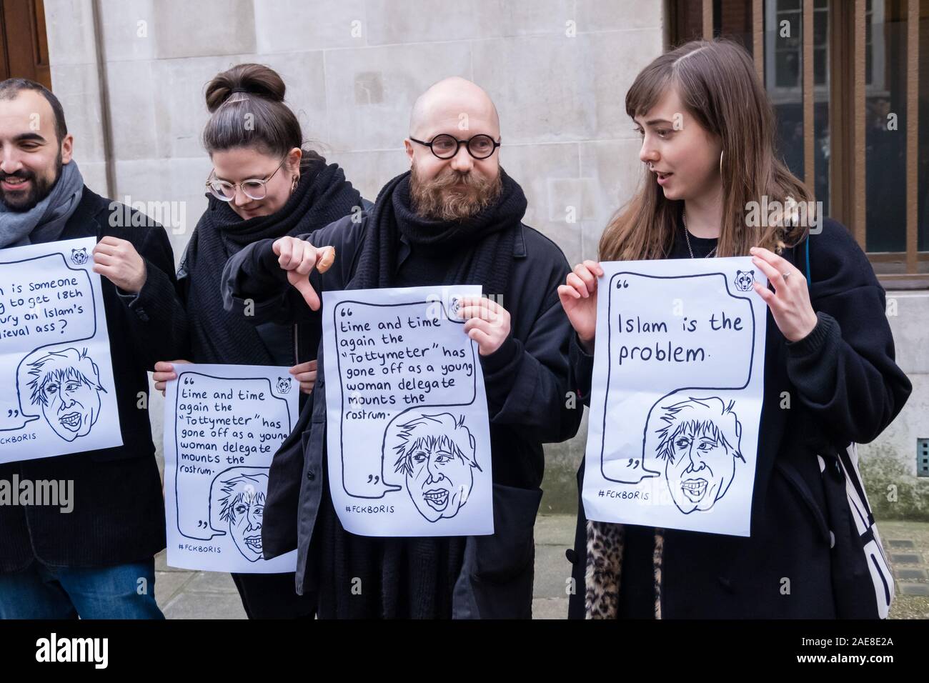 Londra, Regno Unito. Il 7 dicembre 2019. Le persone in attesa di poster con le dichiarazioni offensive realizzato da Boris Johnson. Una volta ha detto: "Se il matrimonio gay è stato OK quindi non ho visto alcun motivo in linea di principio perché un'Unione non dovrebbe essere consacrata tra tre uomini e un cane.' LGBT+ attivisti che hanno preso Boris di etichetta di 'bum boys' celebrare un matrimonio per 3 uomini e un cane fuori Tory HQ la campagna di protesta contro questo e altri suoi omofobi, razzista, ableist e sessista commento prima di marciare per un rally al di fuori di Downing St. Peter Marshall / Alamy Live News Foto Stock