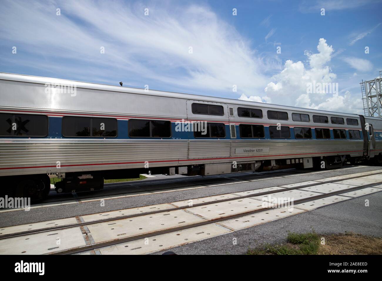 Treno amtrack attraversamento strada dietro barriere alla stazione ferrovia passaggio a livello vicino lago park kissimmee florida usa Foto Stock