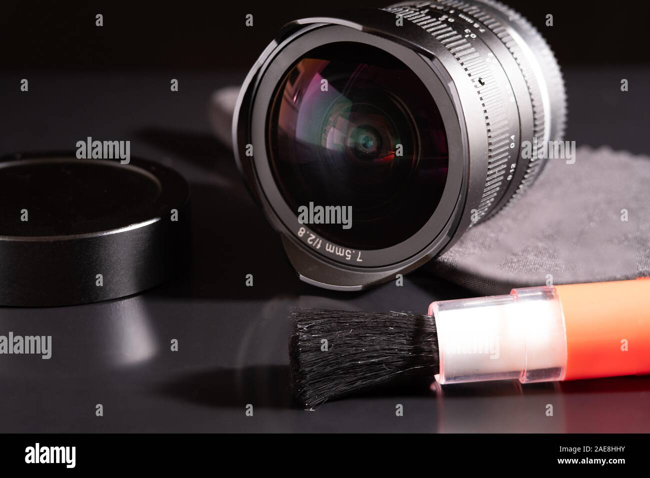 Accessori fotografici al buio su un tavolo. lente e la spazzola di pulizia con una micro fibra assorbente. Foto Stock