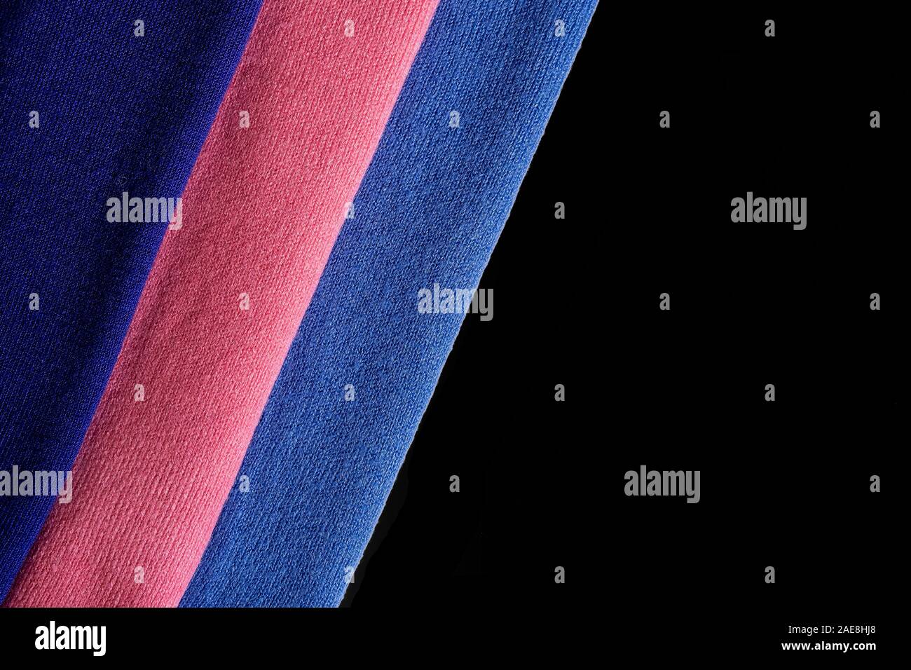 Lavorate a maglia multi-colore di sciarpe close up su uno sfondo nero. Strisce di tessuto. Foto Stock