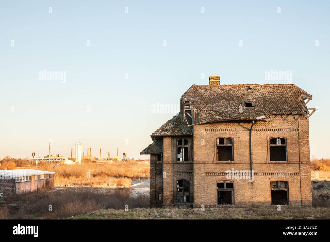Abbandonato casa di fronte vecchie fabbriche e i magazzini con i loro caratteristici camini in Europa Orientale, in Pancevo, Serbia, Ex Jugoslavia, durante una Foto Stock