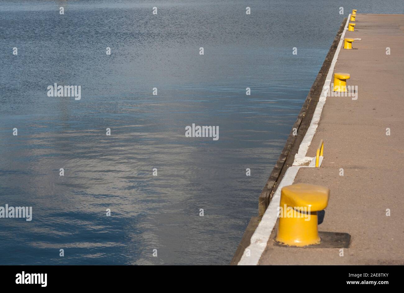 Porto acqua e parte della quey con giallo posti di ormeggio per imbarcazioni come sfondo con spazio di copia Foto Stock