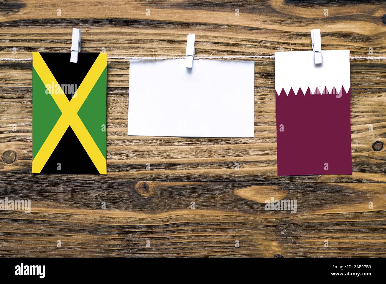 Appendere bandiere della Giamaica e Qatar attaccata alla corda con vestiti perni con copia spazio bianco sulla nota carta su sfondo di legno.Le relazioni diplomatiche essere Foto Stock