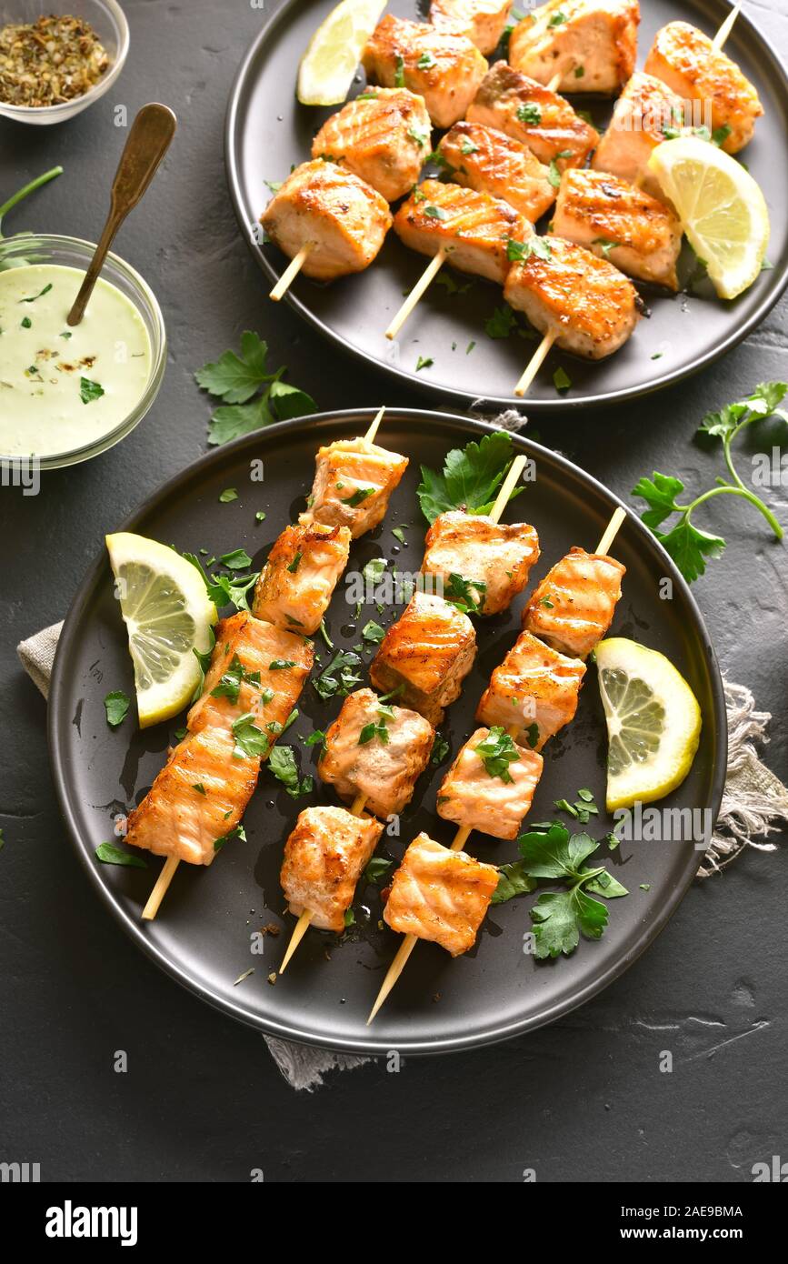 Salmone alla griglia kebab. Barbecue spiedini di salmone su pietra scura sullo sfondo. Foto Stock