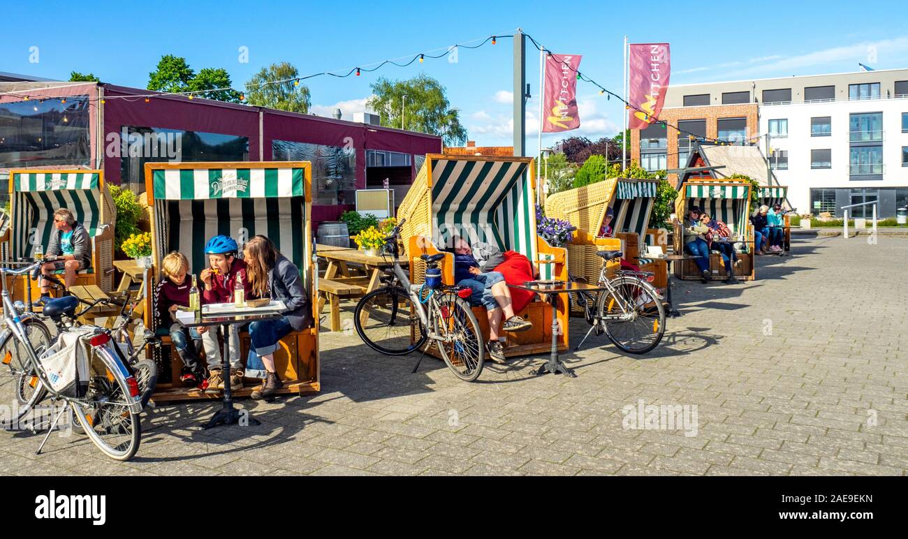 Ciclisti che riposano e che hanno un rinfresco all'aperto seduti in vimini Strandkorbs a Glückstadt Schleswig-Holstein Germania Foto Stock