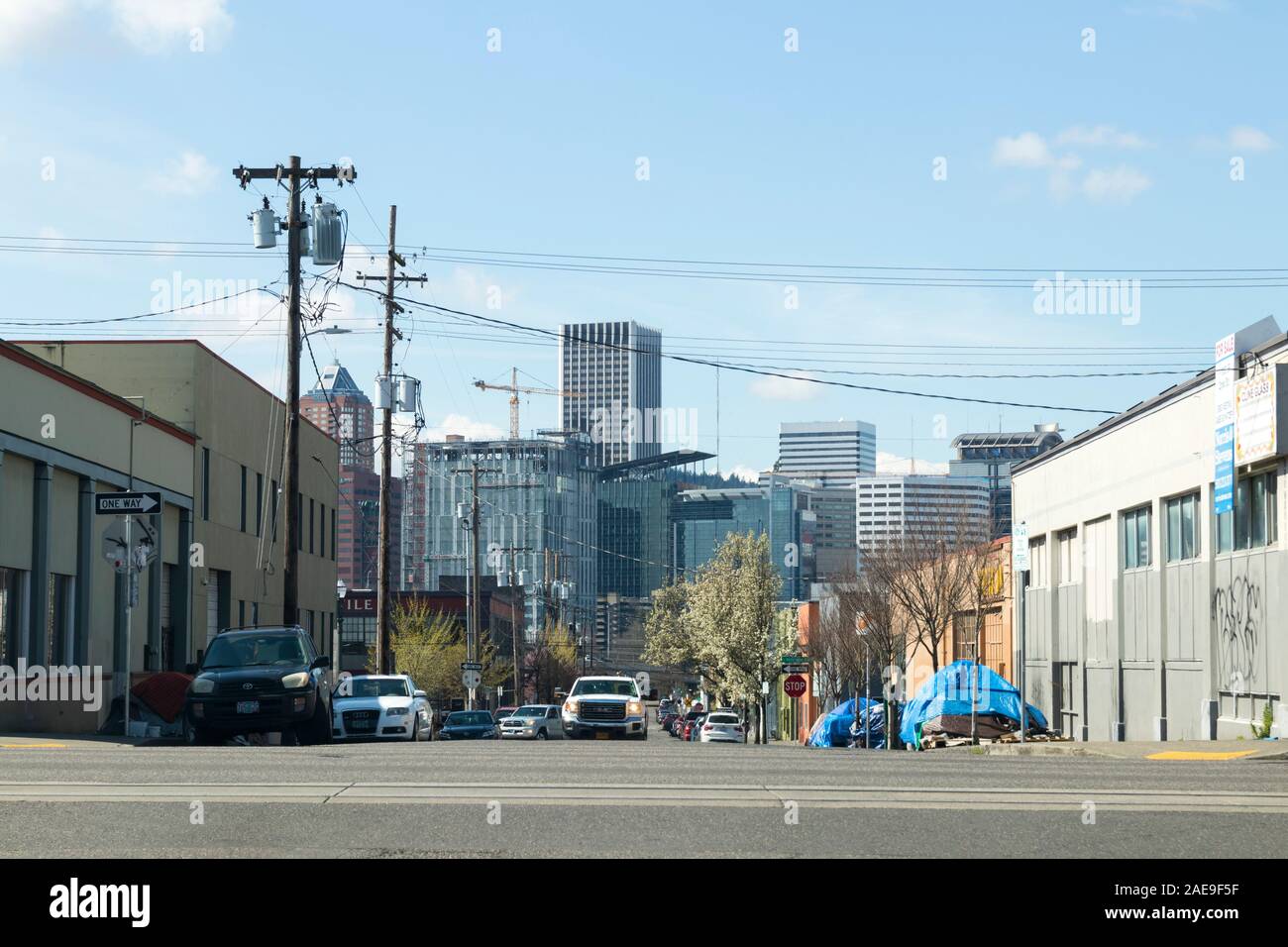 Portland, Oregon / STATI UNITI D'AMERICA - Circa 2019: senzatetto tende sul marciapiede accanto a una strada e Portland Oregon skyline della città visibile in lontananza. Foto Stock