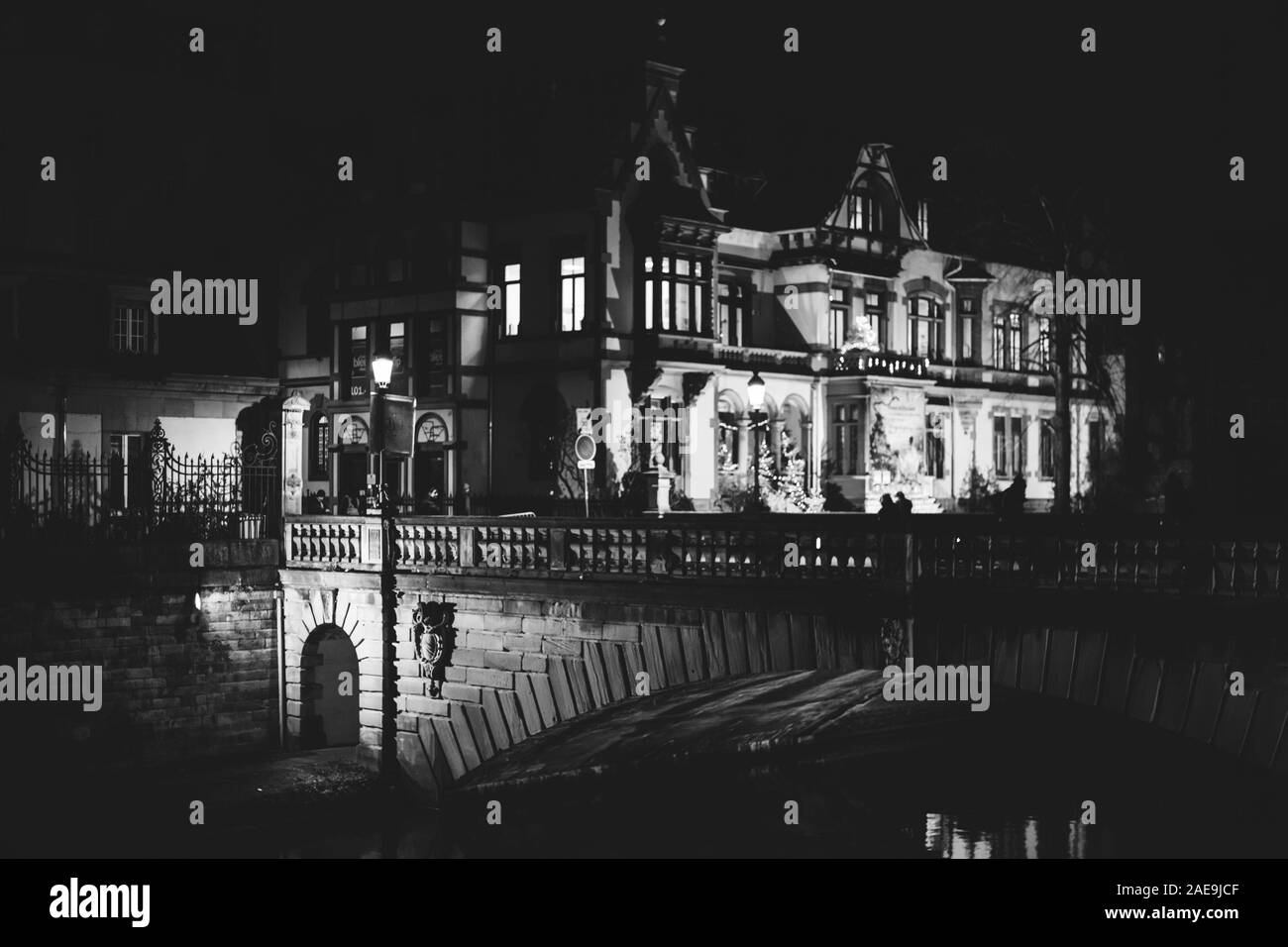Strasburgo, Francia - Dic 20, 2016: illuminato dalla luce di strada Pont de la Poste nel centro di Strasburgo con Radio Francia alsaziano legno costruzione casa sullo sfondo - Immagine in bianco e nero Foto Stock