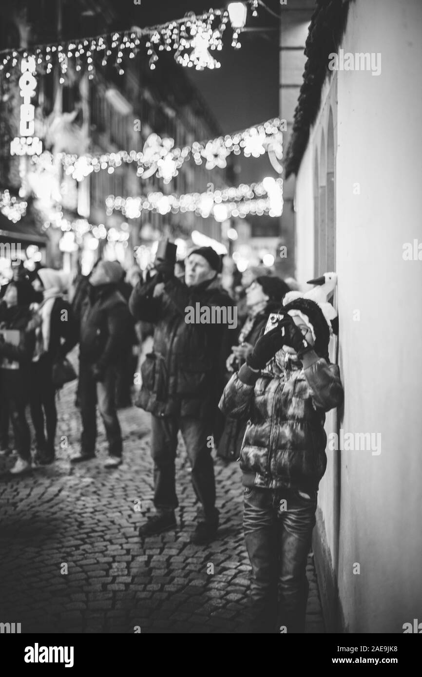 Strasburgo, Francia - Dic 20, 2016: francese street con la donna prendendo fotografia sullo smartphone della movimentata Rue du Maroquin decorate luminarie bokeh di fondo per il Mercato di Natale Foto Stock