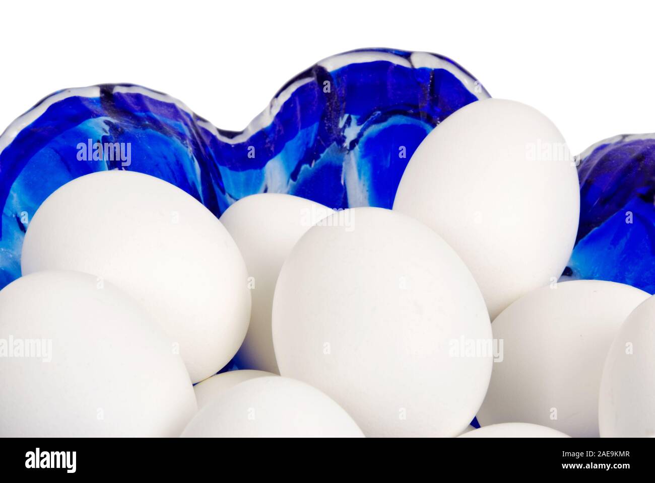 Colorate di bianco uova sode nel blu di una ciotola di vetro isolato su un fondo bianco. Foto Stock