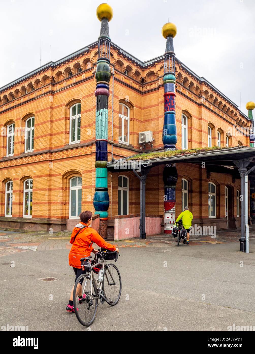 Ciclisti in visita alla stazione ferroviaria di Bahnhof Uelzen, ristrutturata dall'architetto Friedensreich Hundertwasser bassa Sassonia Germania. Foto Stock