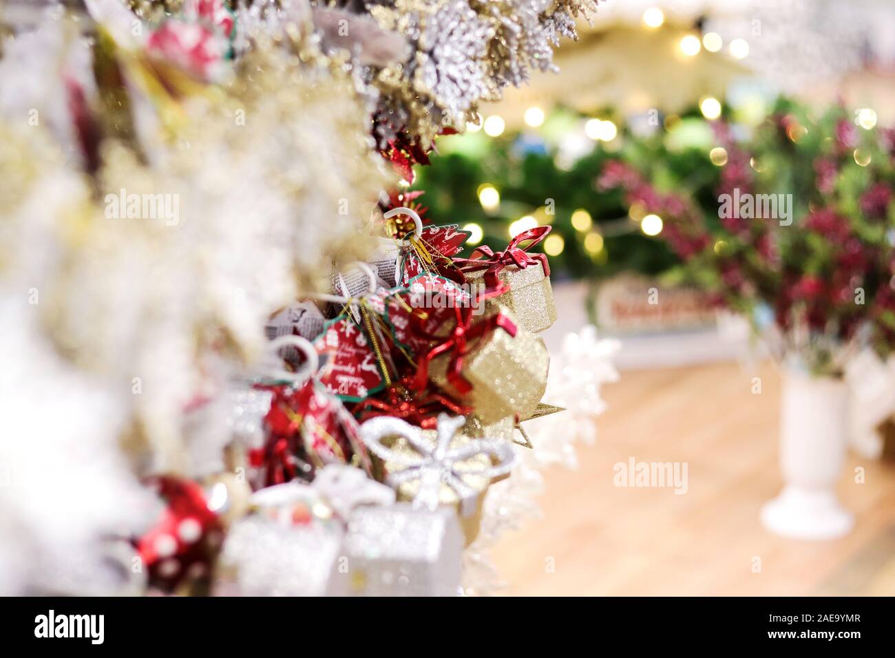 Shopping di Natale morbido sfondo selettivo del fuoco per l'oro piccolo e bianco decorazione dell'albero di Natale splendente in negozio di regali. Foto Stock