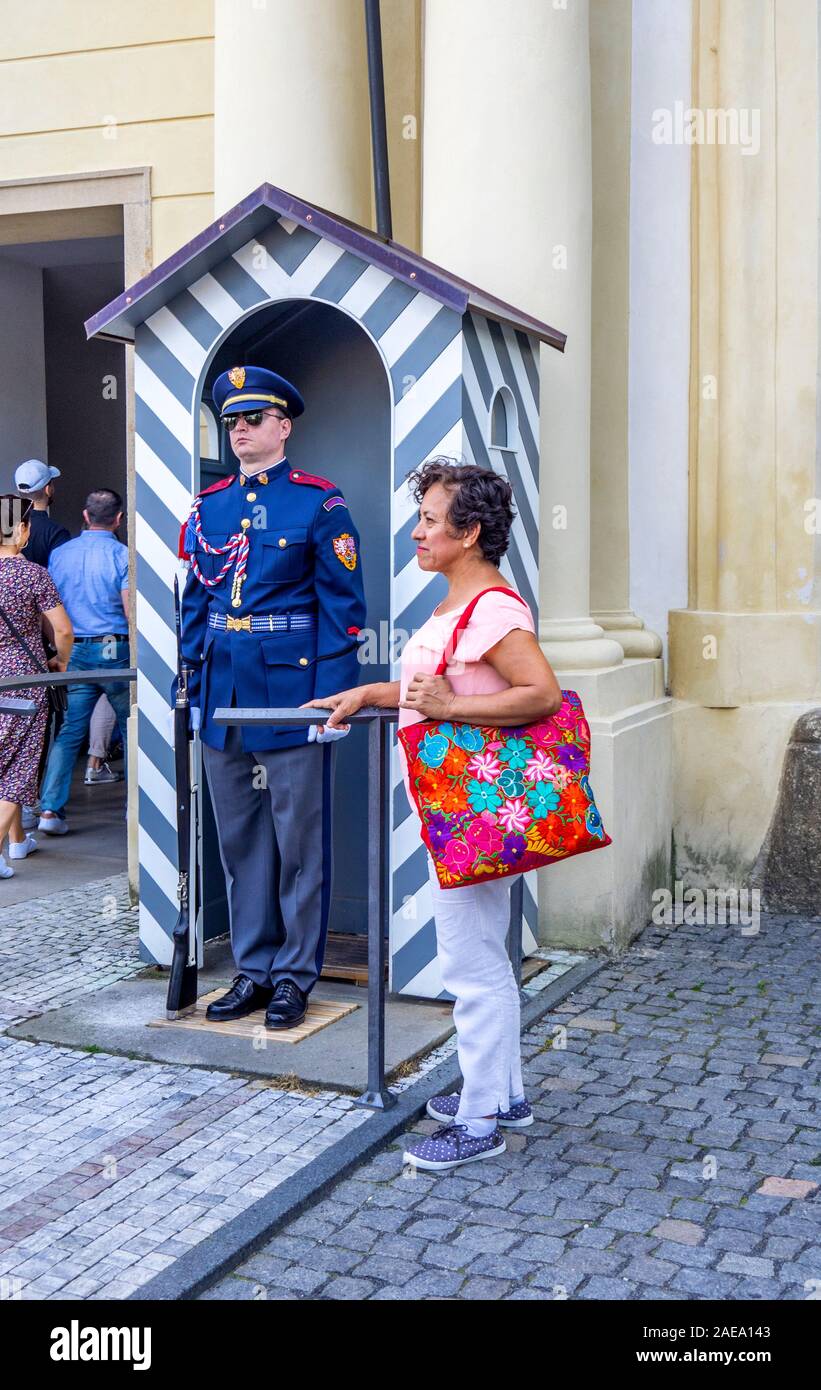 Donna turistica posa per fotografia in piedi dalla Guardia del Castello di Praga di fronte al box di sentinella le Scuderie imperiali entrata Praga Repubblica Ceca. Foto Stock