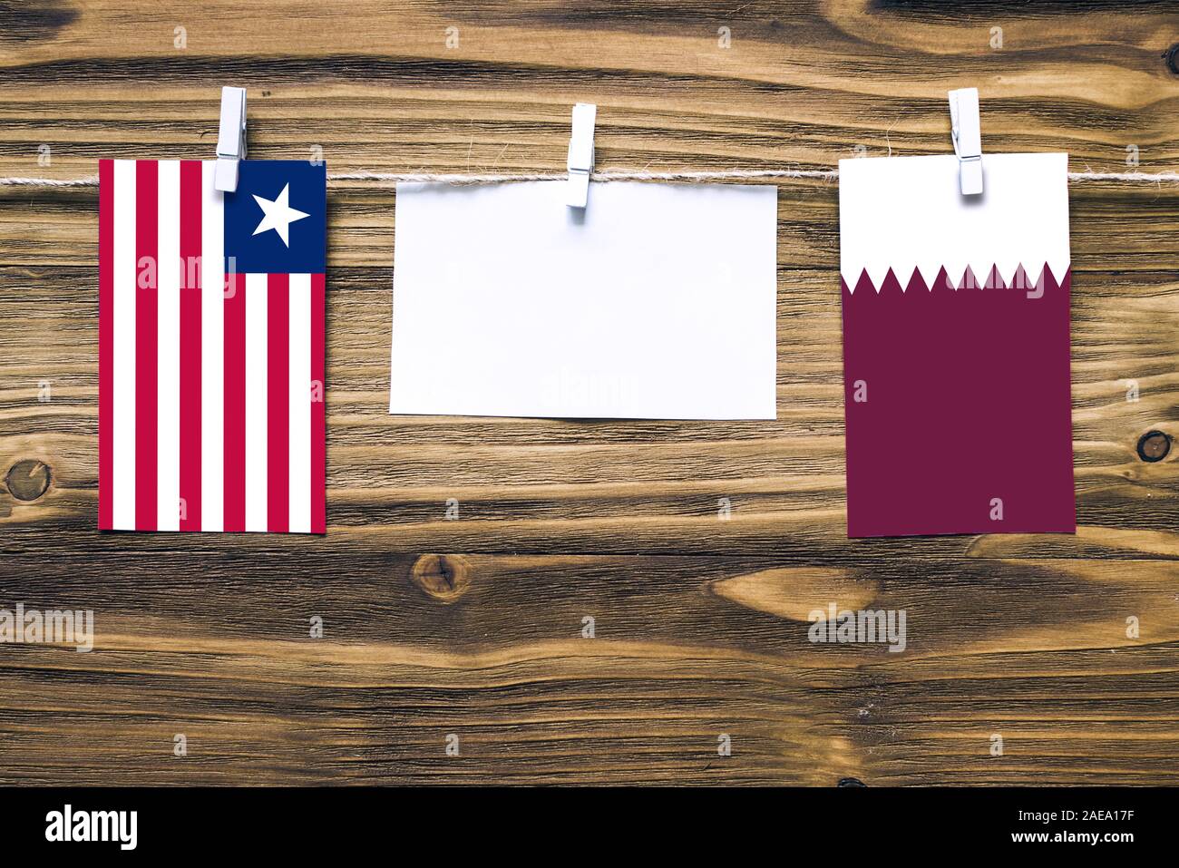 Appendere bandiere della Liberia e del Qatar attaccata alla corda con vestiti perni con copia spazio bianco sulla nota carta su sfondo di legno.Le relazioni diplomatiche essere Foto Stock