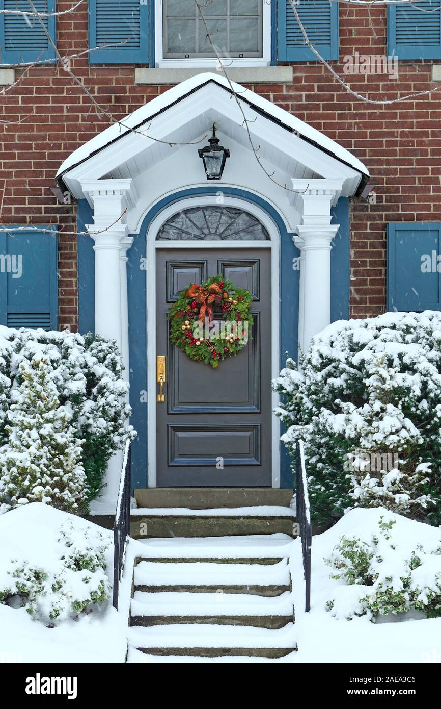 Sportello anteriore della coperta di neve casa con la ghirlanda di Natale Foto Stock