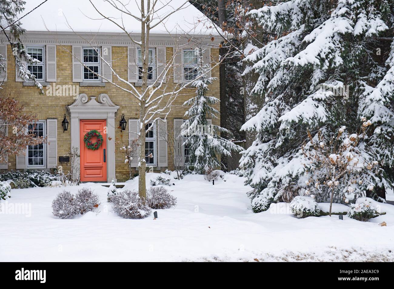 Sportello anteriore della coperta di neve casa con la ghirlanda di Natale Foto Stock