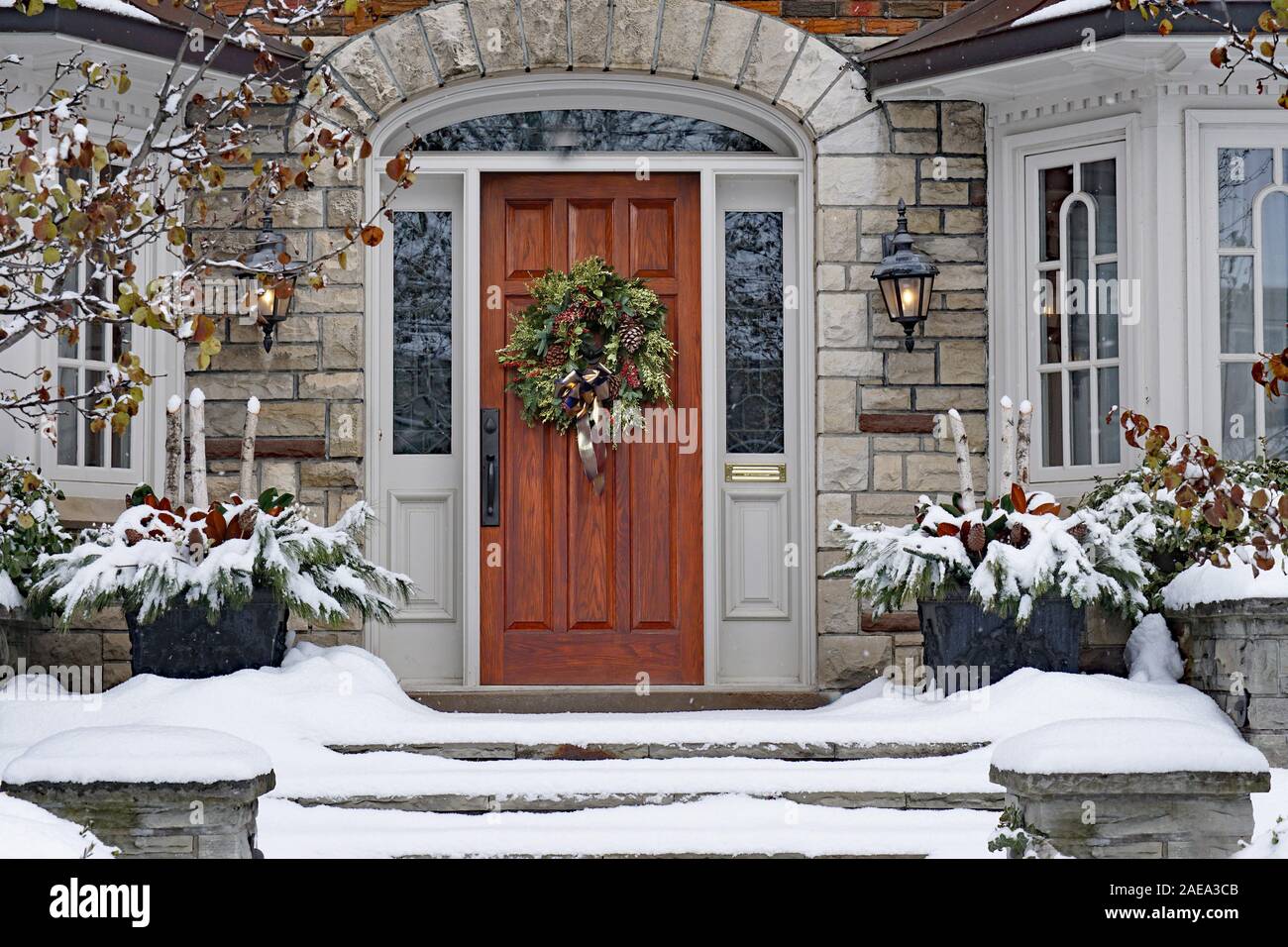 Sportello anteriore della coperta di neve casa con la ghirlanda di Natale Foto Stock