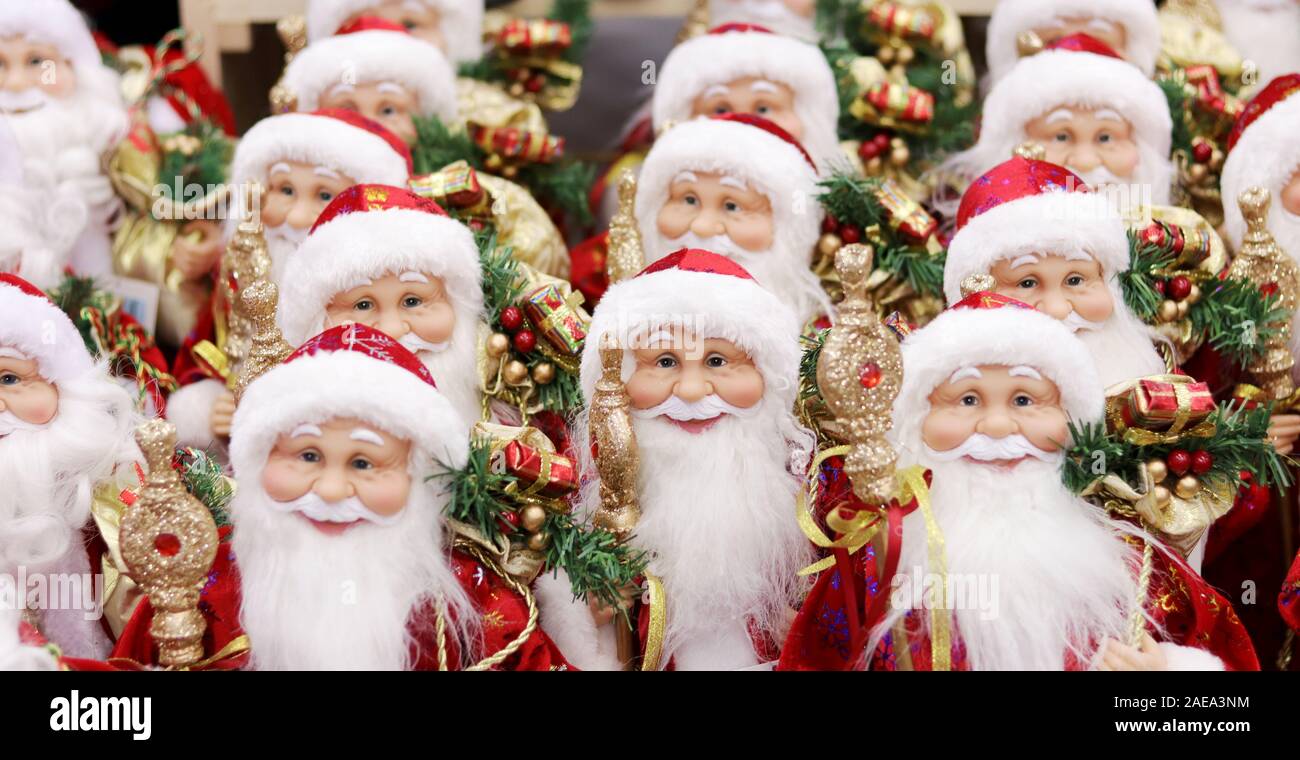 Esercito di Santa clausole figure giocattolo in abiti rossi con regali e bastoni. Buon Natale sfondo morbido fuoco foto. Foto Stock