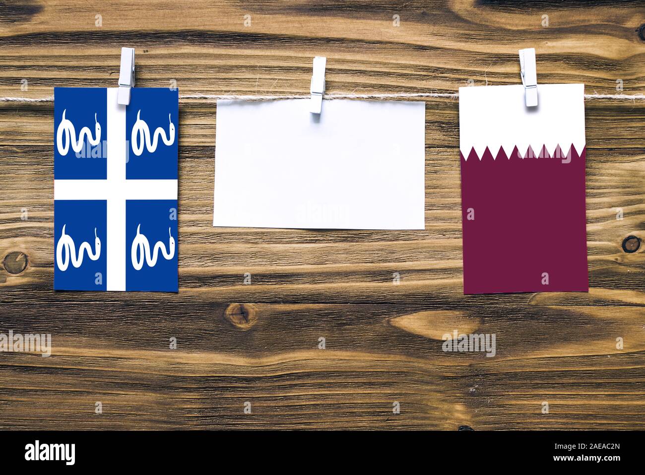 Appendere bandiere della Martinica e in Qatar attaccata alla corda con vestiti perni con copia spazio bianco sulla nota carta su sfondo di legno.Le relazioni diplomatiche Foto Stock
