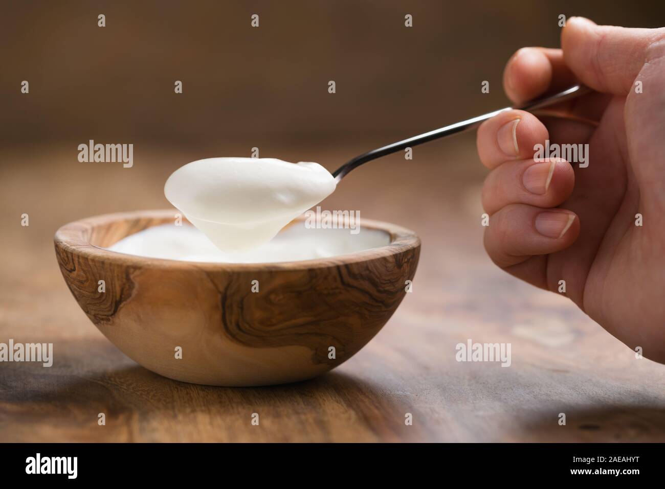 Pov shot del giovane femmina mano con cucchiaio colmo di yogurt seduti a tavola, fondale focus Foto Stock