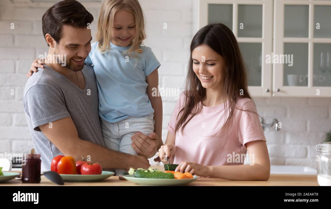 Moglie di cetriolo tagliato per insalata e parlare con la famiglia Foto Stock