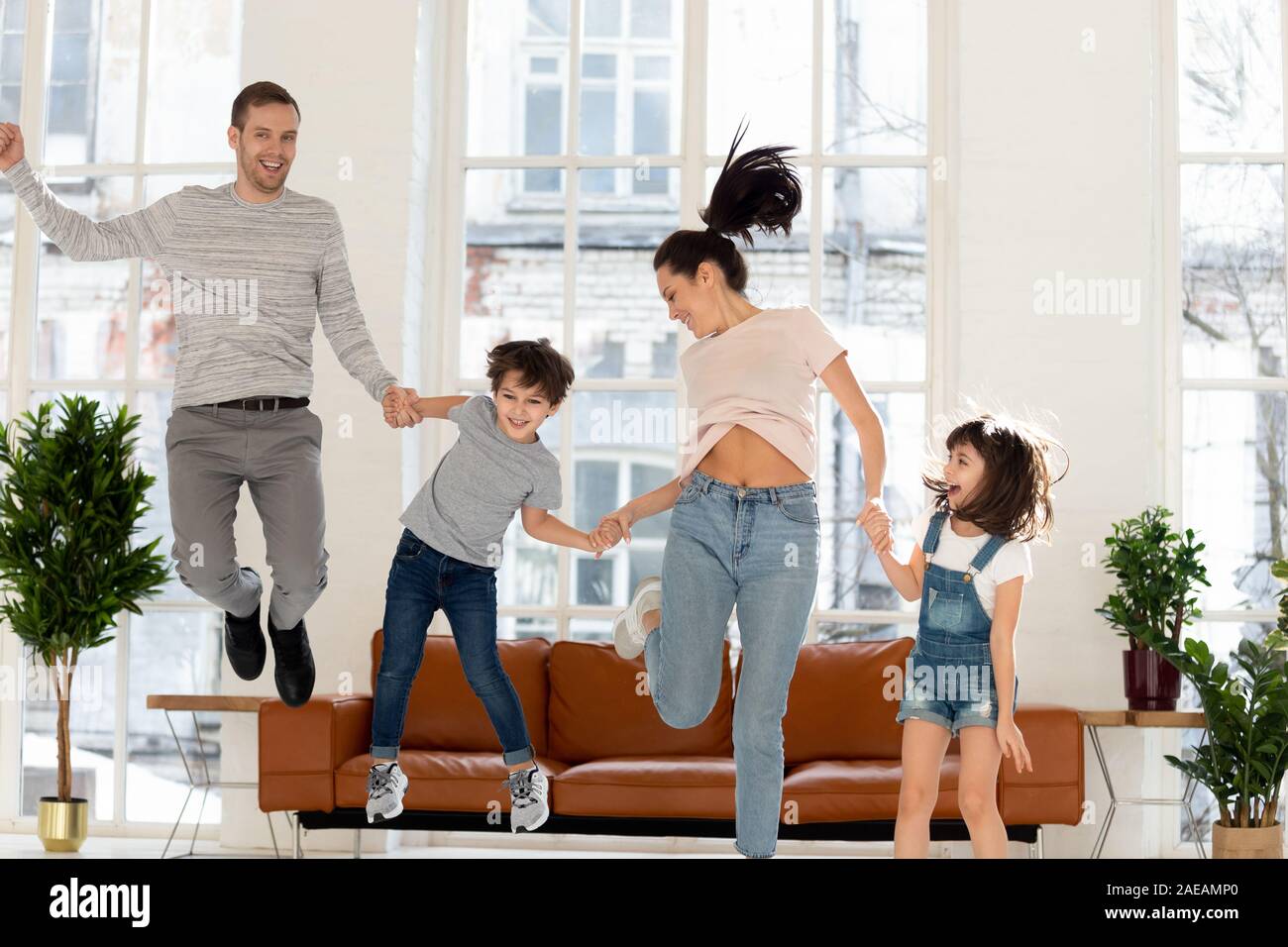 Felice famiglia con due bambini jumping a casa. Foto Stock