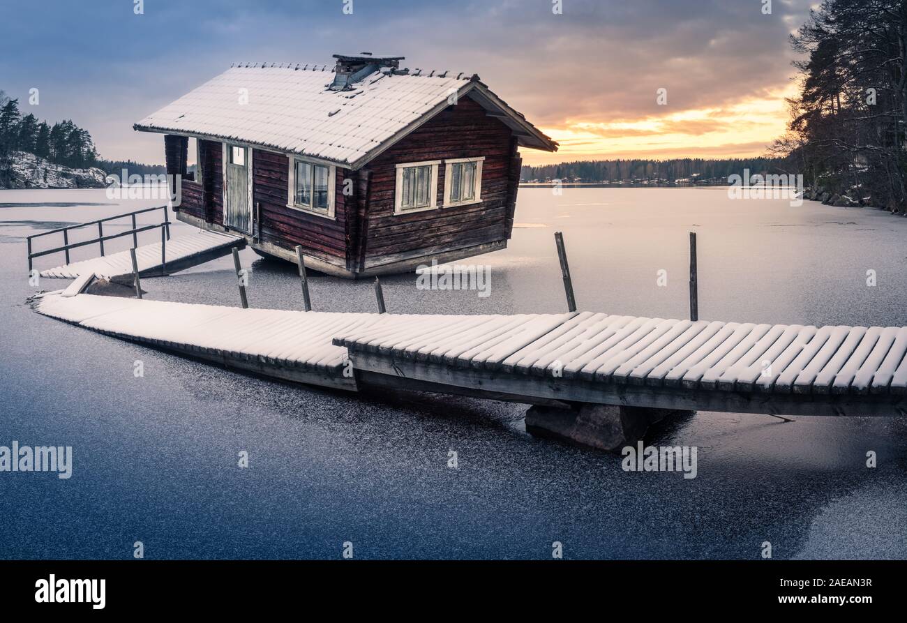 Abbandonata la sauna e il molo rotto con panorama al tramonto di sera d'inverno in Finlandia Foto Stock