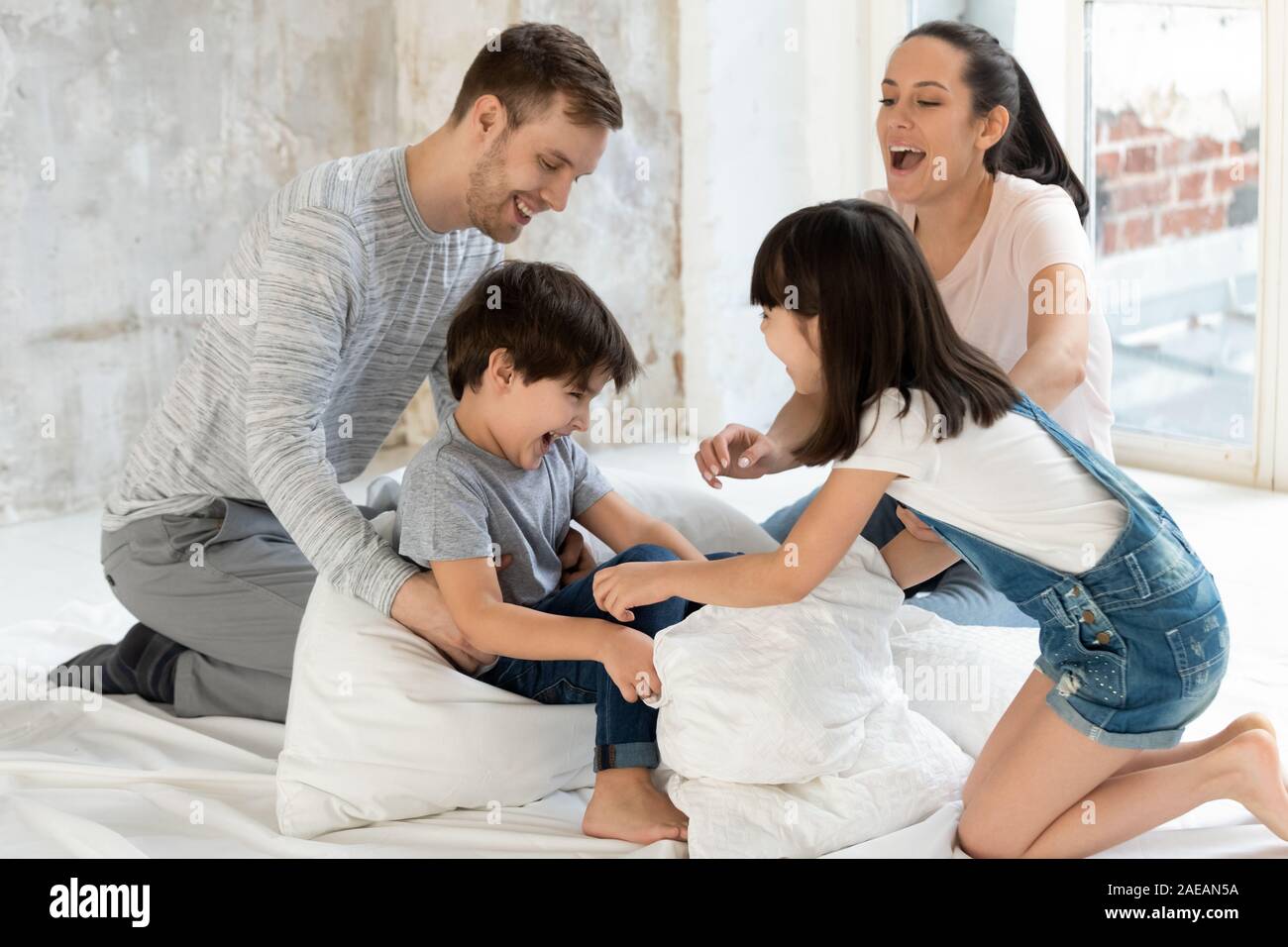 La famiglia felice tickle bambini e avente un buon tempo sul letto. Foto Stock