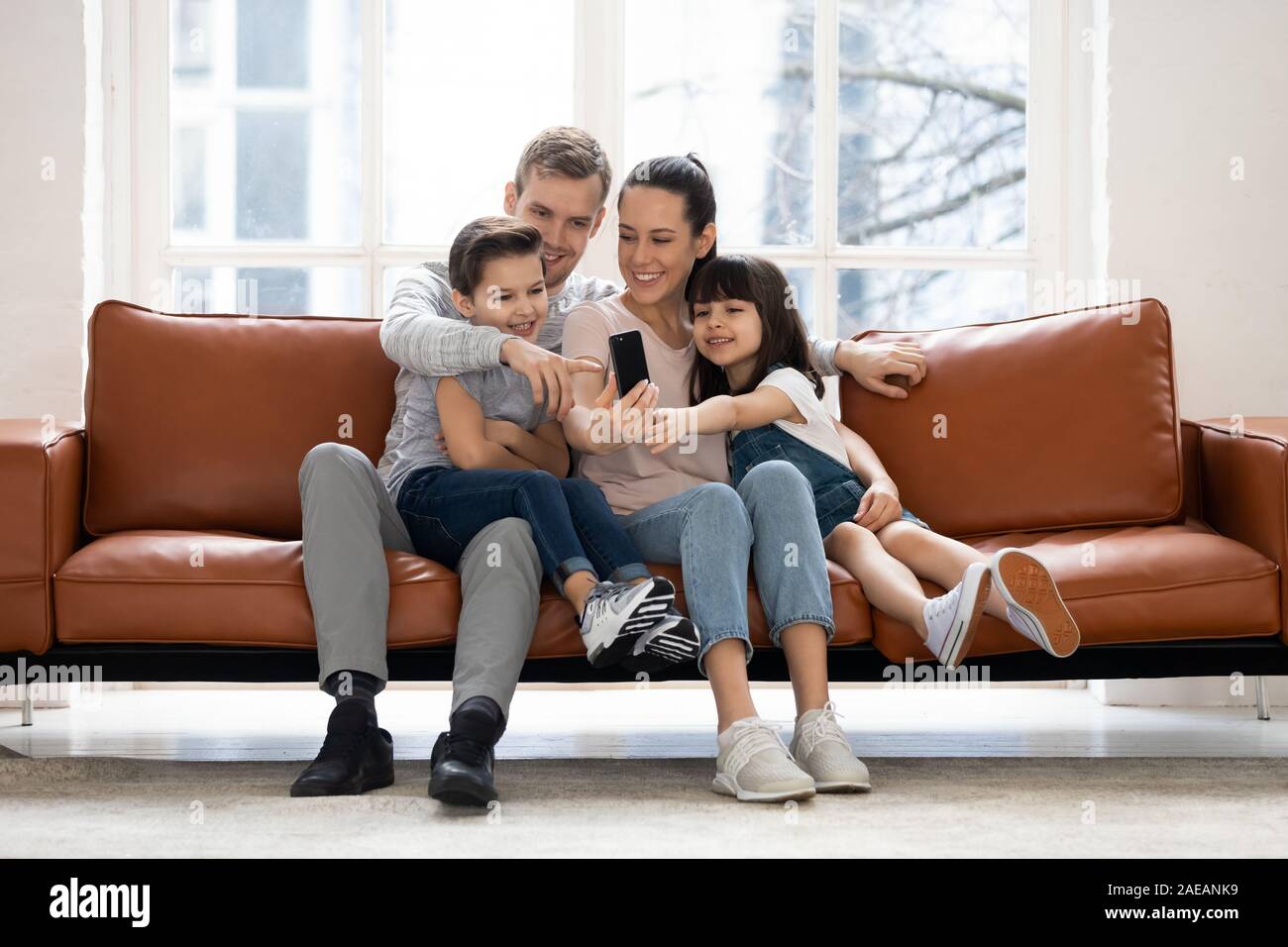 Felice famiglia con due bambini avente una buona volta utilizzando lo smartphone. Foto Stock