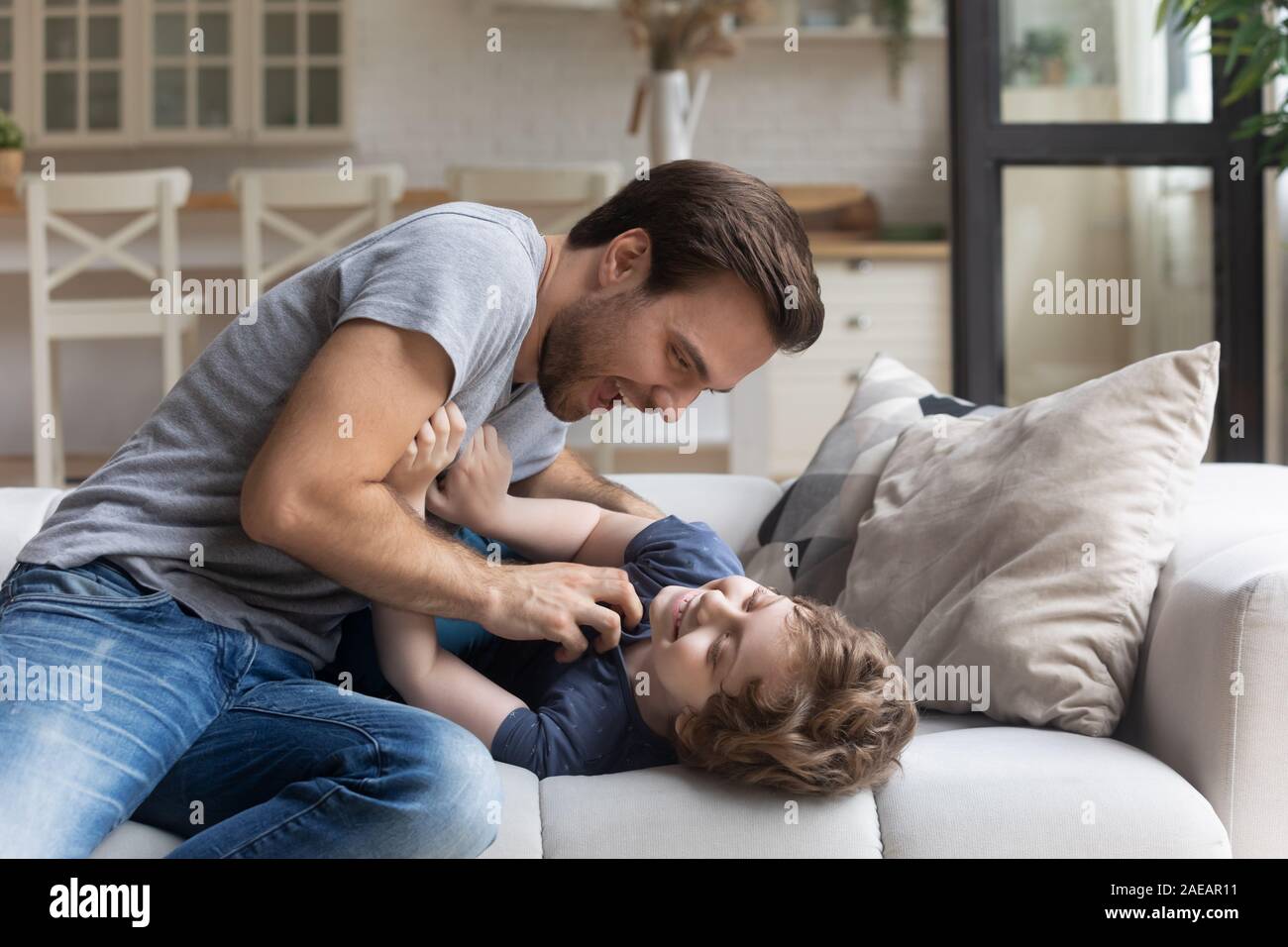 Padre solletica adorabile figlio divertendosi in salotto Foto Stock