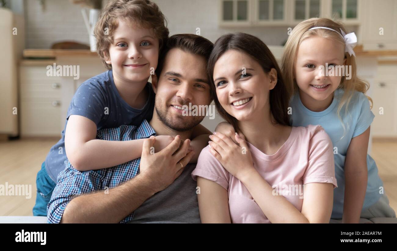 Sorridente coppia con bambini seduti sul divano in posa per la fotocamera Foto Stock