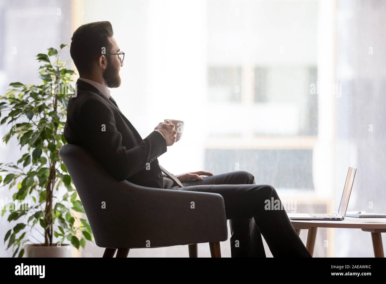 Imprenditore arabo guarda nella distanza prendendo break in ufficio Foto Stock