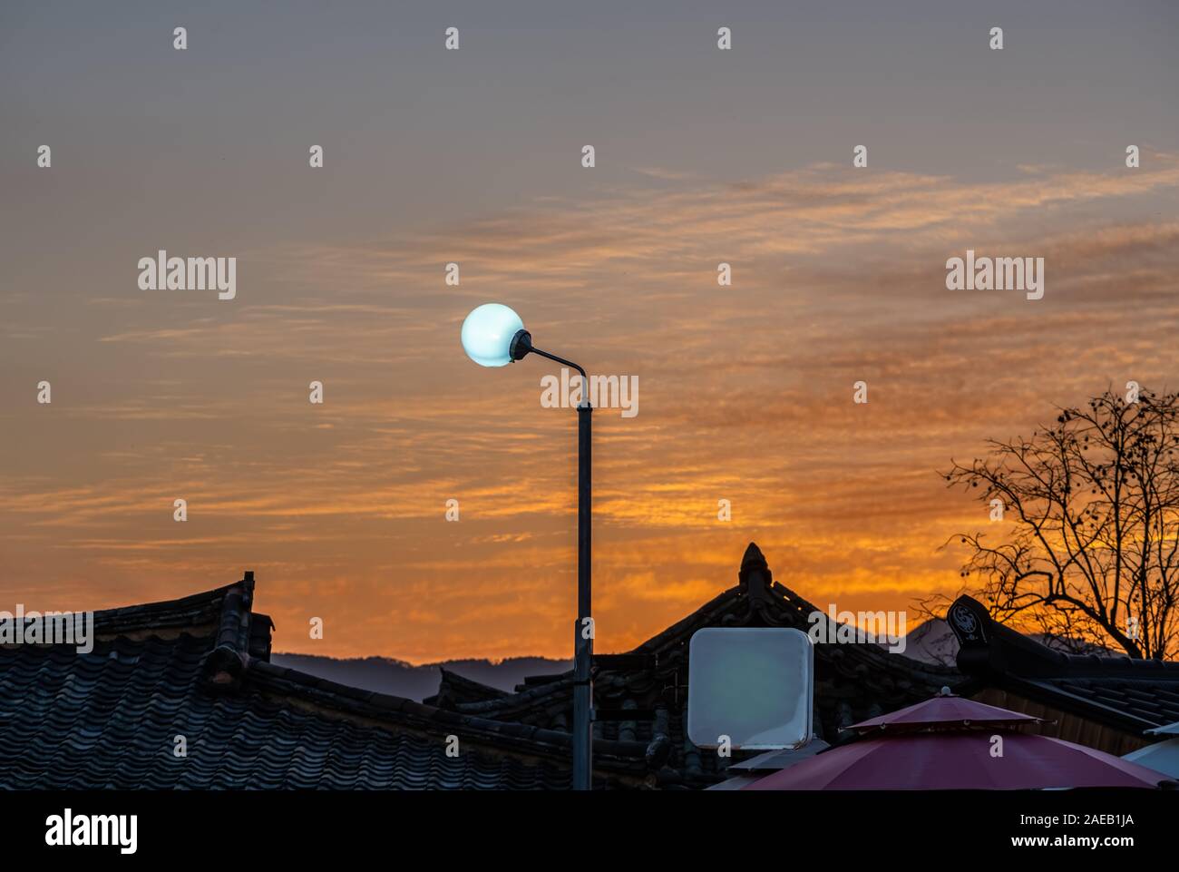 Un solitario strada lampada oltre il tradizionale Coreana di tetti di tegole. Foto Stock