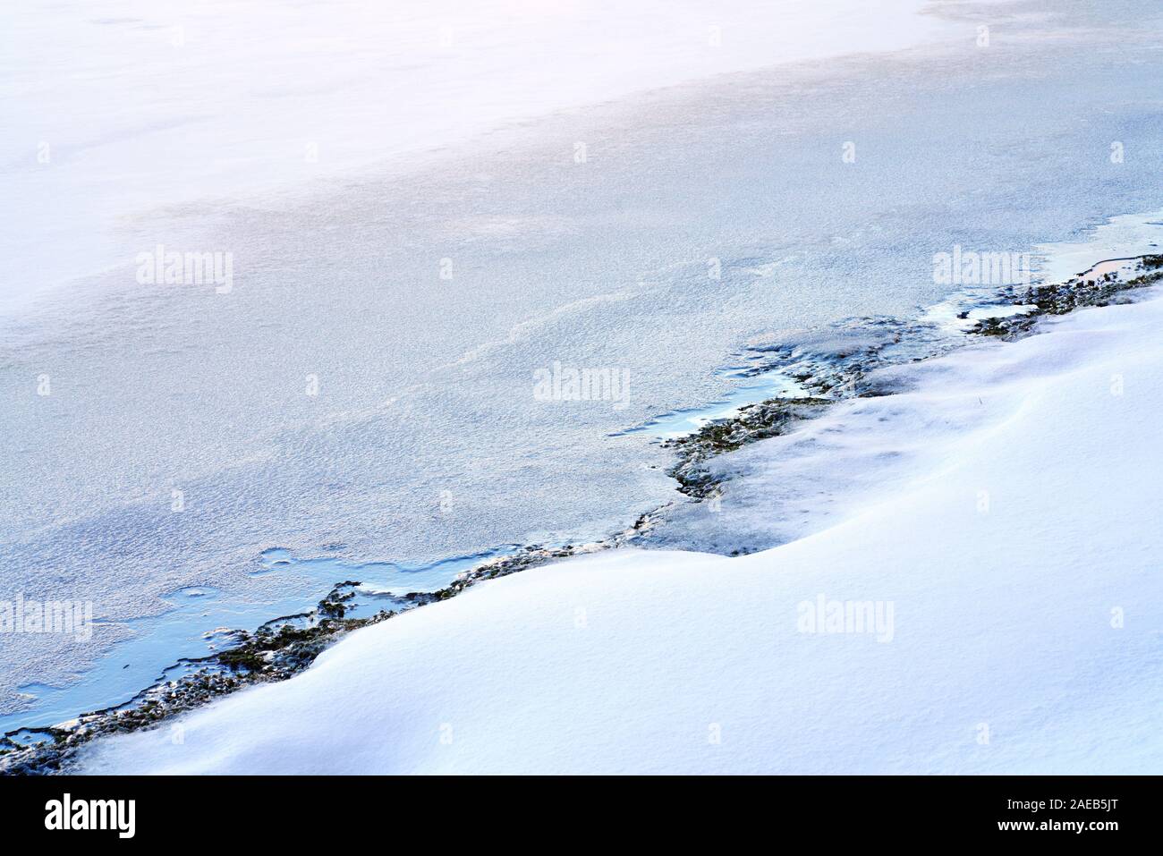 Blue Ice soddisfa il bianco della neve. La superficie ghiacciata di un lago incontra la coperta di neve sul lago. Bellissimo tema invernale, paesaggio invernale dello sfondo. Foto Stock