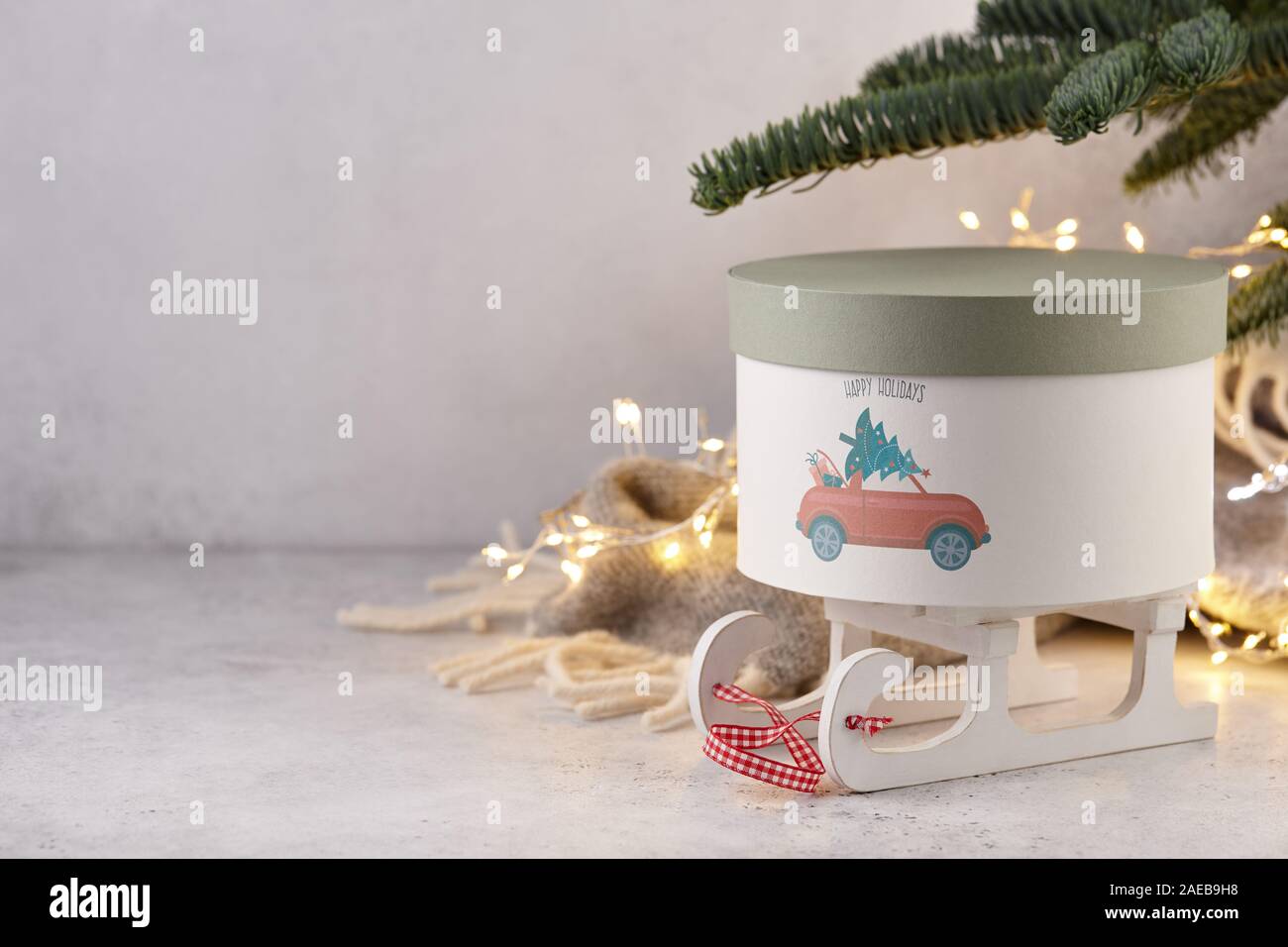 Confezione regalo con holiday car stampa sotto albero di Natale sulla coperta di lana e luci di sfondo, spazio di copia Foto Stock