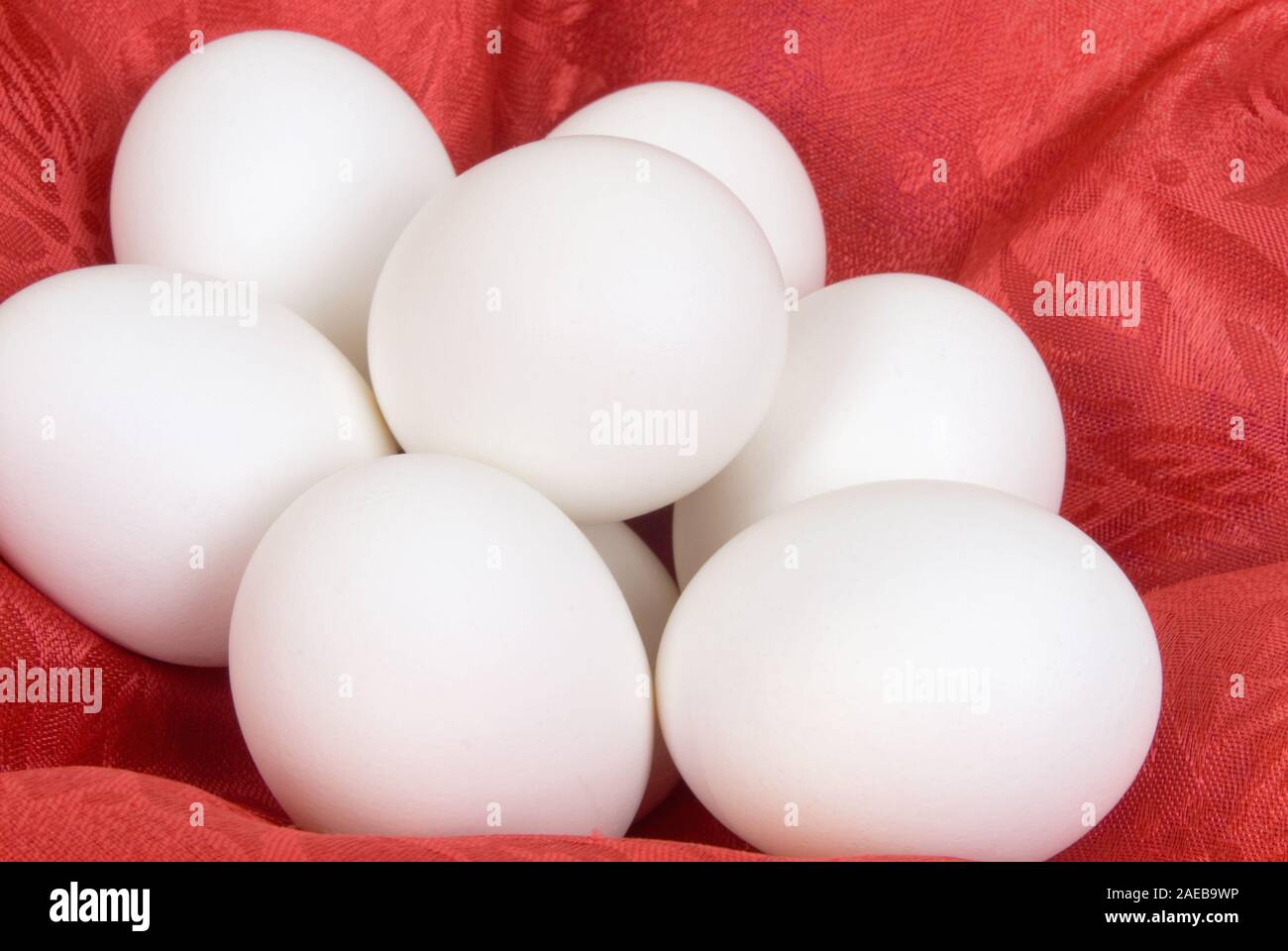 Gruppo di bianco uova sode su un rosso tessuto di seta textured background. Foto Stock